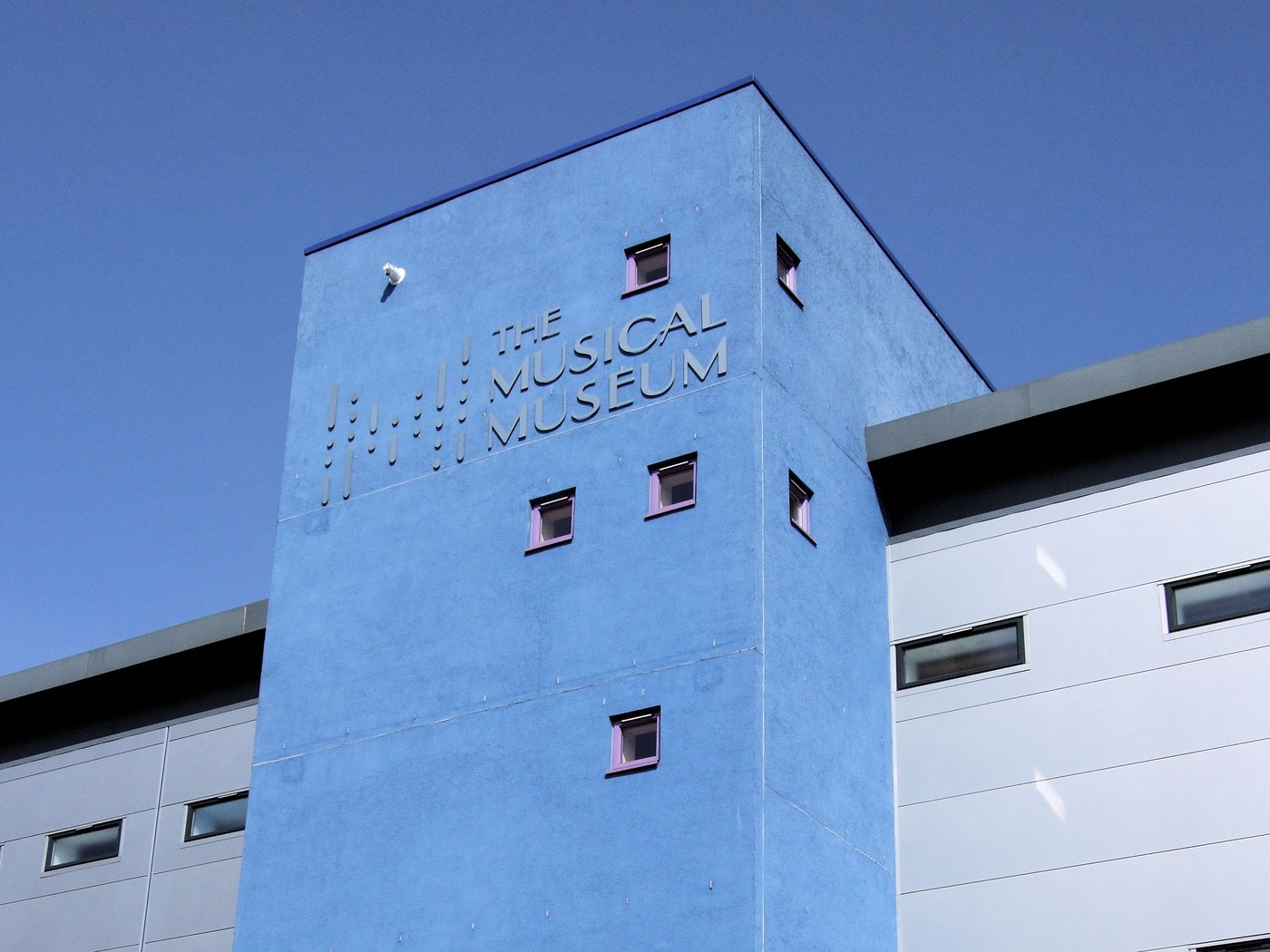 Exterior of The Musical Museum building in Brentford, showing its signage on a blue-clad tower